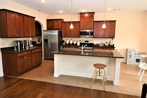 a kitchen with kitchen island granite countertop wooden cabinets and refrigerator