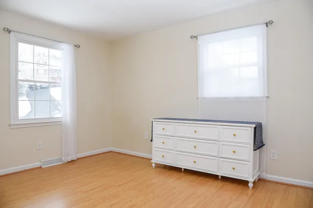 a view of an empty room with a window and dresser
