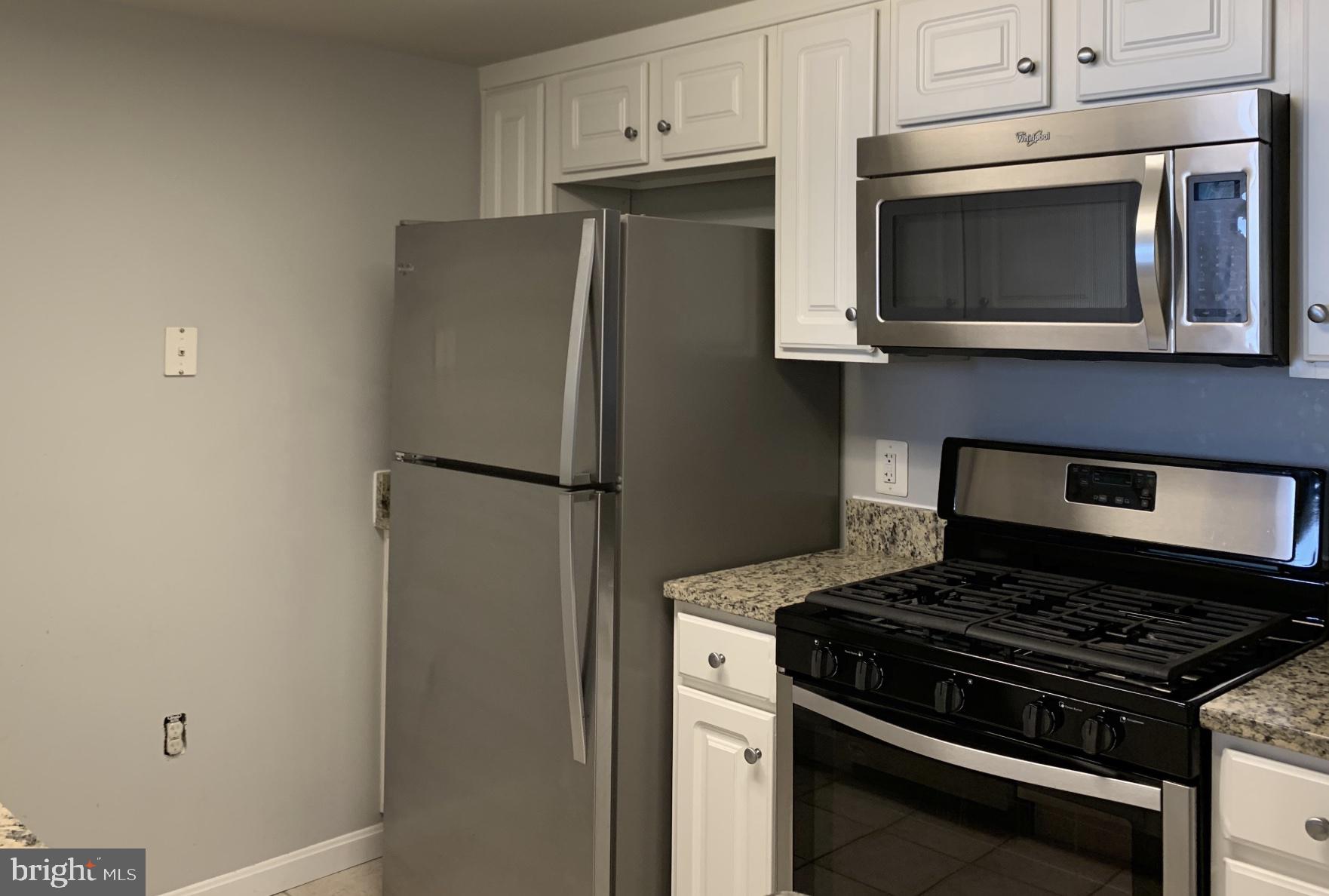 11710 Old Georgetown Road, Unit 1012 North Bethesda, MD 20852 - Photo 3 of 6 a kitchen with stainless steel appliances white cabinets and a stove top oven