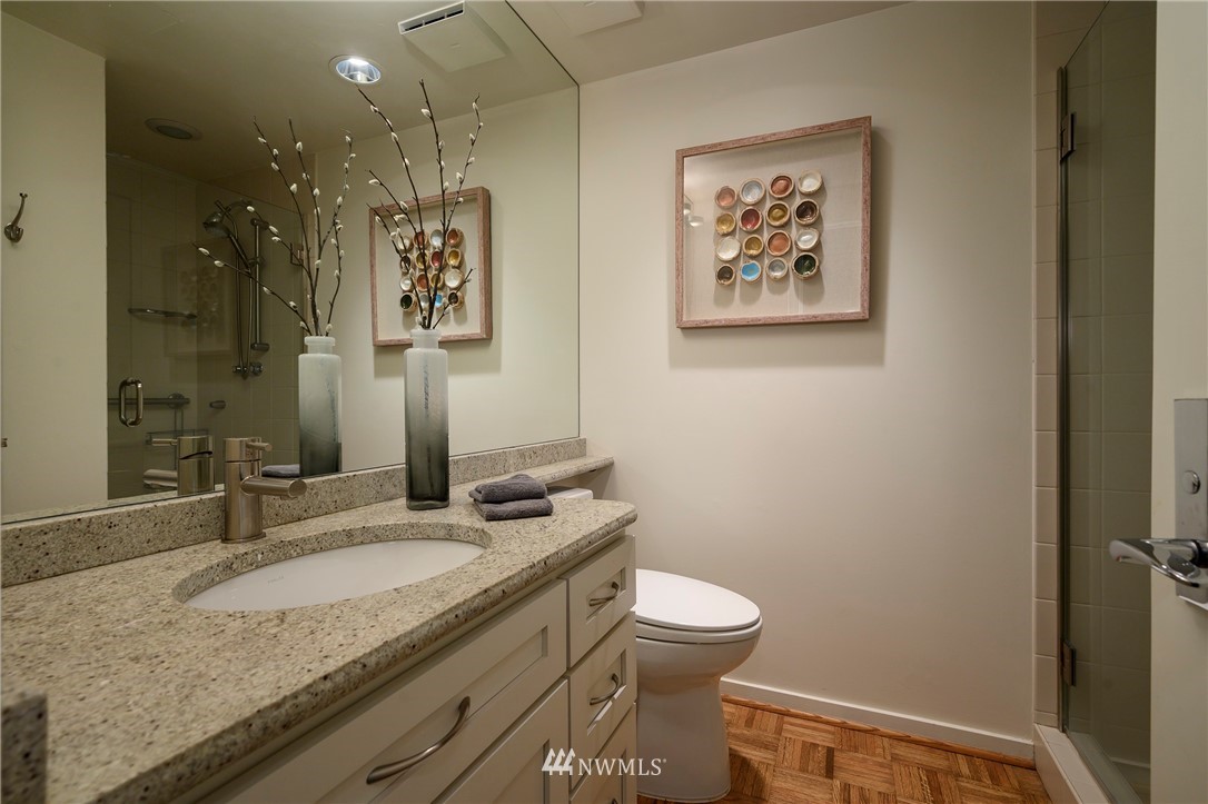 1301 Spring Street, Unit 20G Seattle, WA 98104 - Photo 11 of 24 a bathroom with a granite countertop sink a toilet and a mirror