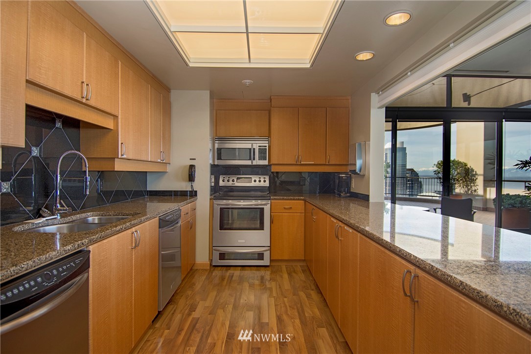 1301 Spring Street, Unit 20G Seattle, WA 98104 - Photo 16 of 24 a kitchen with stainless steel appliances granite countertop a stove a sink and a microwave