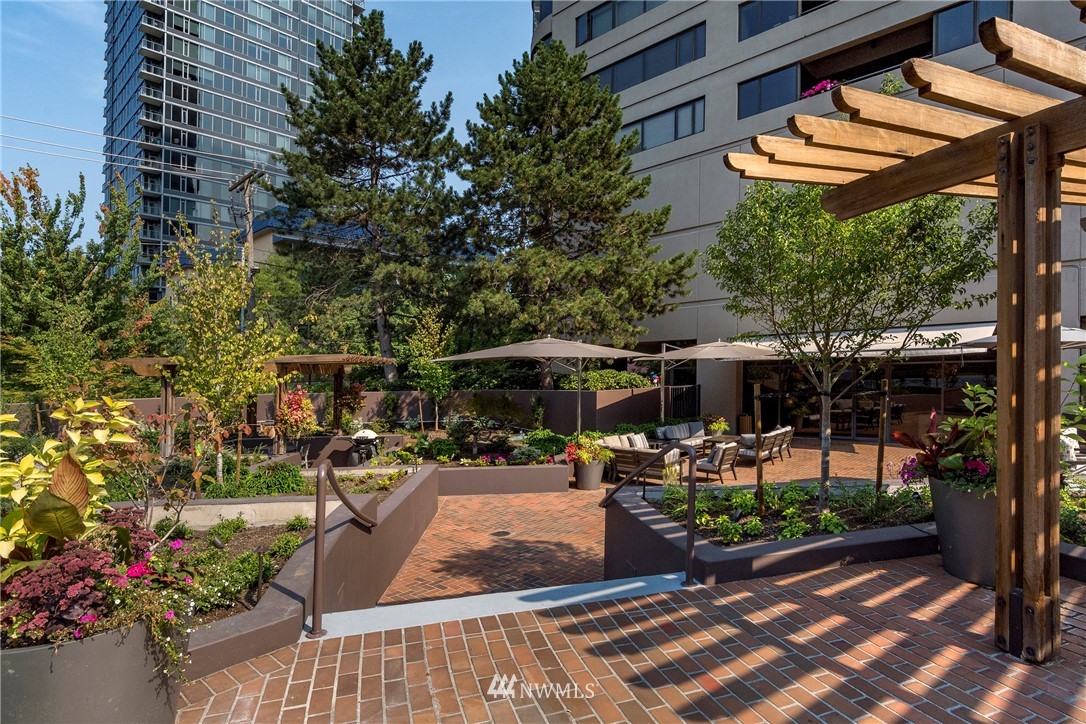 1301 Spring Street, Unit 20G Seattle, WA 98104 - Photo 22 of 24 a view of a patio with table and chairs potted plants and large tree