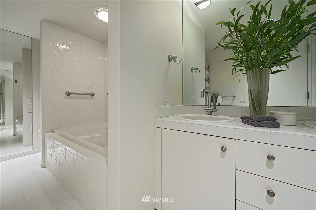 1301 Spring Street, Unit 20G Seattle, WA 98104 - Photo 8 of 24 a bathroom with a granite countertop sink a mirror a vanity and a bathtub