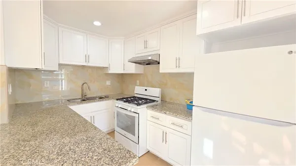 a kitchen with granite countertop a sink a stove and cabinets