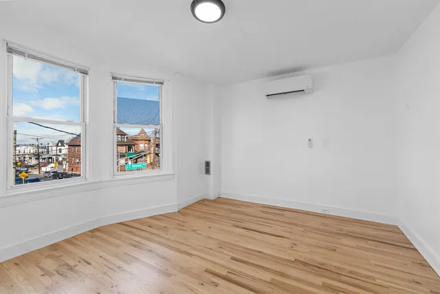 a view of empty room with window and painting on the wall