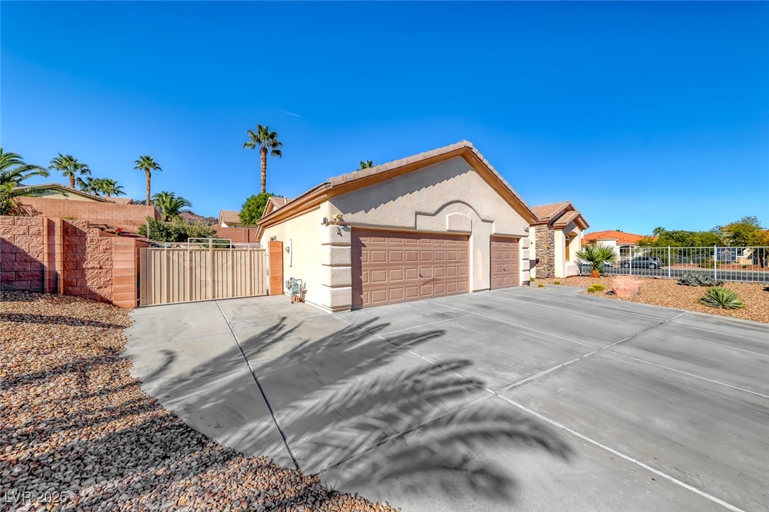 698 Magic Cove Court Boulder City, NV 89005 - Photo 3 of 41 View of front of home featuring a gate, stucco siding, concrete driveway, an attached garage, and stone siding