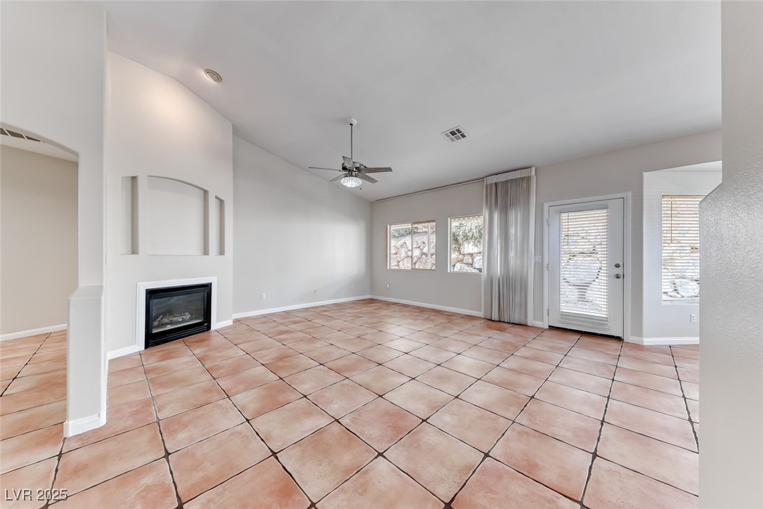 698 Magic Cove Court Boulder City, NV 89005 - Photo 33 of 41 Unfurnished living room featuring lofted ceiling, light tile patterned floors, a ceiling fan, and a glass covered fireplace