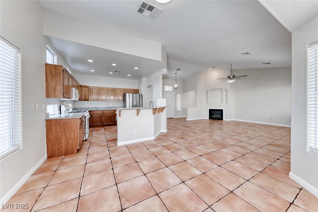 698 Magic Cove Court Boulder City, NV 89005 - Photo 41 of 41 Kitchen featuring light countertops, brown cabinetry, ceiling fan, light tile patterned floors, and open floor plan