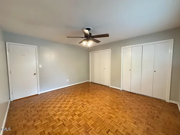 a view of an empty room and chandelier fan
