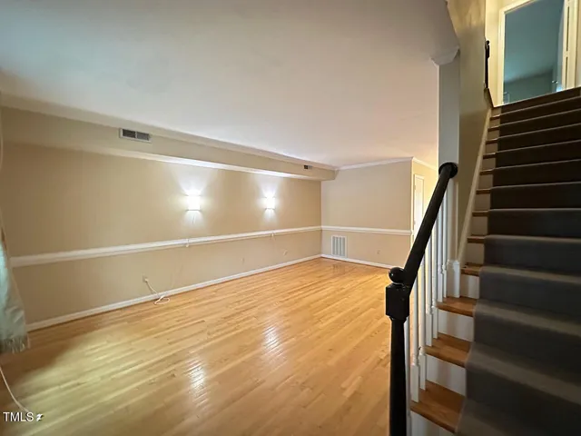 a view of an empty room with stairs and wooden floor