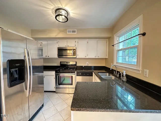a kitchen with granite countertop a stove a sink and a microwave