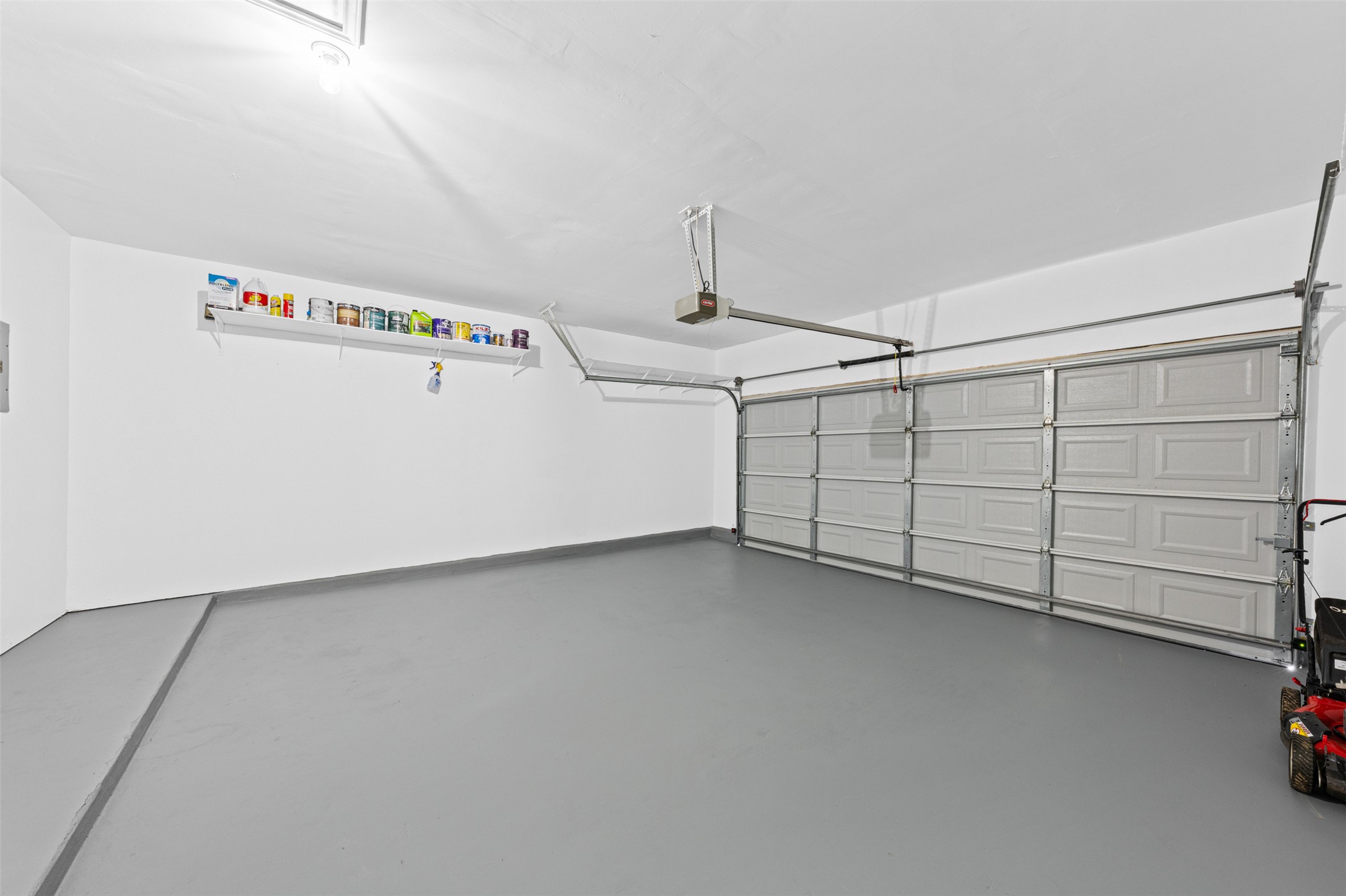 243 Engineers Pass Jarrell, TX 76537 - Photo 34 of 40 Spacious two-car garage featuring a painted concrete floor, white walls, and an overhead lighting fixture