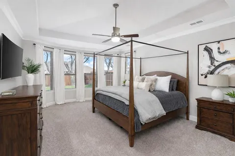 a spacious bedroom with a bed window and flat screen tv