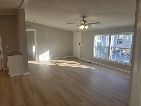 a view of an empty room with wooden floor and a window
