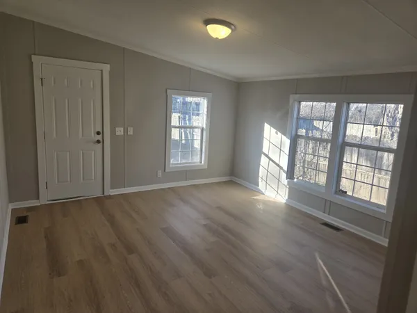 an empty room with wooden floor and windows