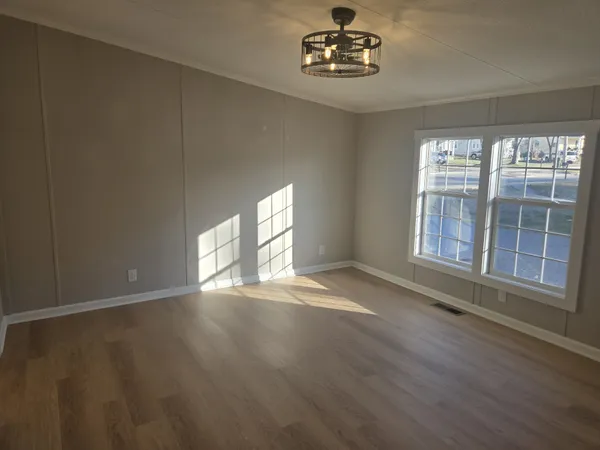 a view of an empty room with a window and wooden floor