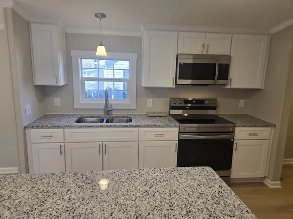 a kitchen with stainless steel appliances granite countertop a sink stove a microwave and a refrigerator