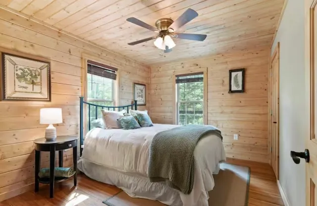 a bedroom with a bed large window with table and chair