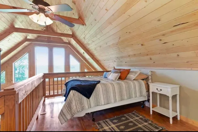 a view of a bedroom with a bed and wooden floor