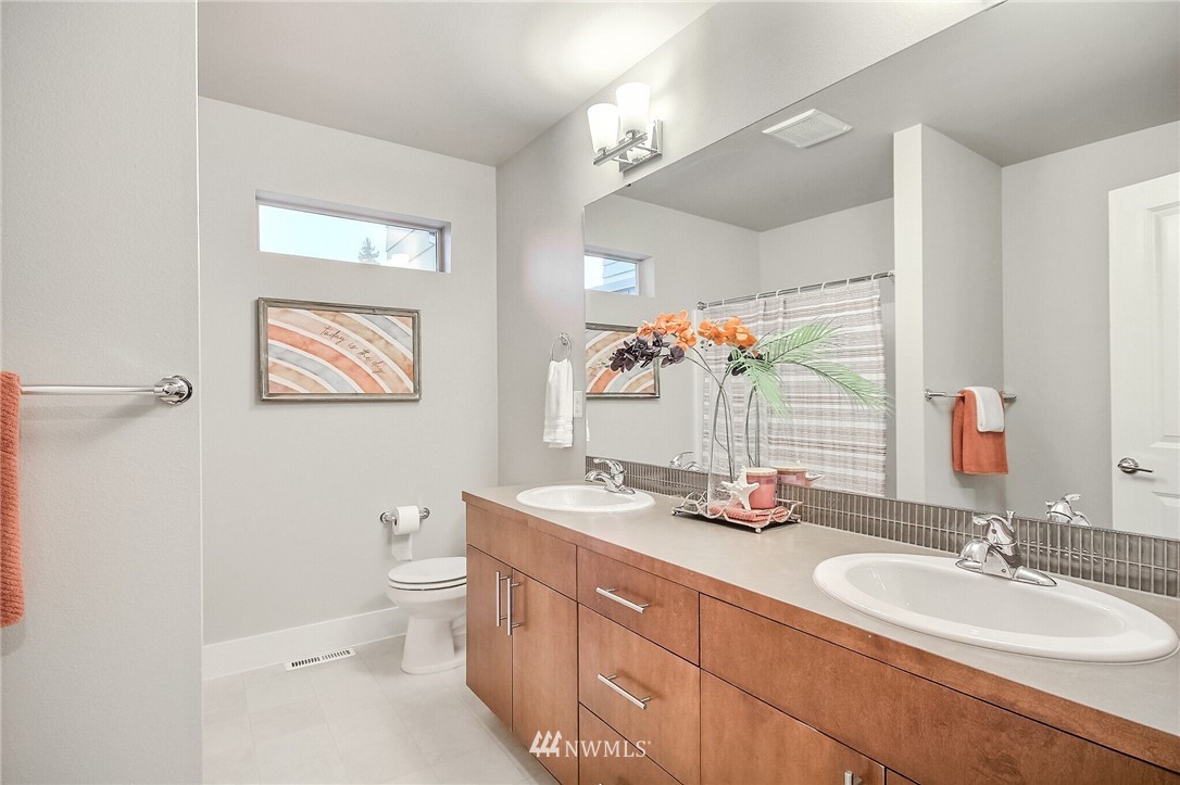 5113 Northeast 11th Place Renton, WA 98059 - Photo 34 of 40 a bathroom with double vanity sink a mirror and a toilet