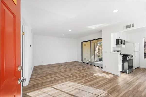 a view of a livingroom with wooden floor and a refrigerator