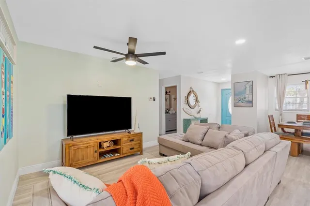 a living room with furniture a ceiling fan and a flat screen tv