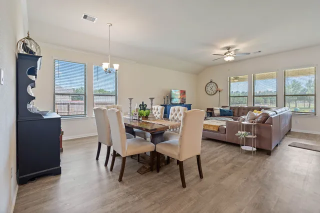 a living room with furniture a dining table and a floor to ceiling window