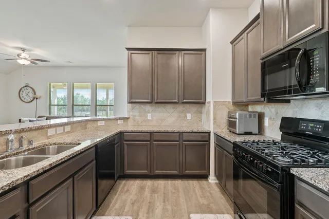 a kitchen with stainless steel appliances granite countertop a refrigerator and a stove top oven