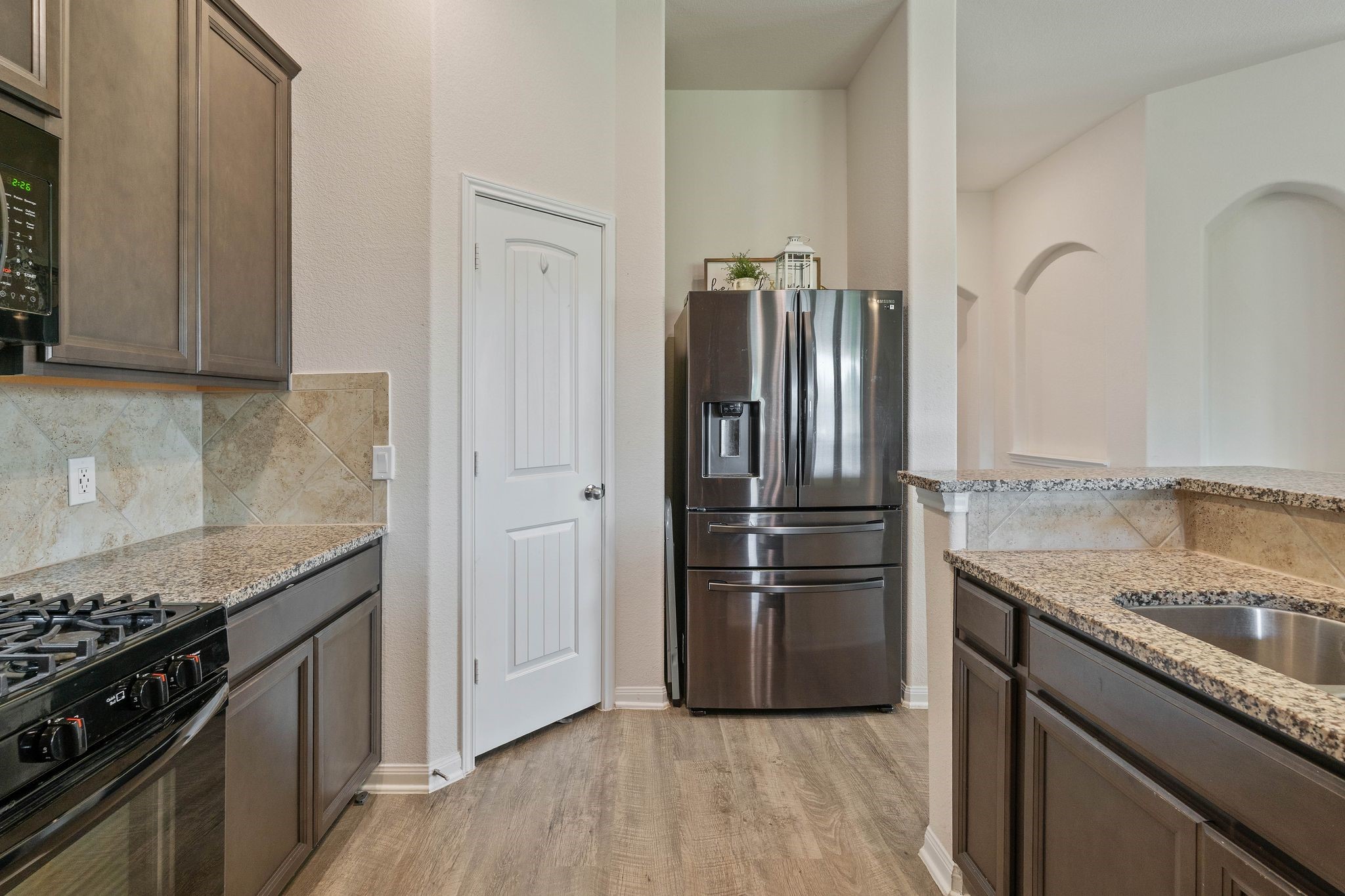 16450 Stonewall Street Conroe, TX 77303 - Photo 17 of 43 Alternate kitchen perspective displaying pantry area and arched art niches.