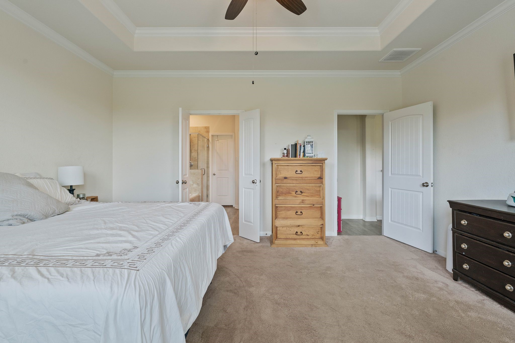 16450 Stonewall Street Conroe, TX 77303 - Photo 18 of 43 Spacious primary bedroom with tray ceiling, ceiling fan, and natural light.