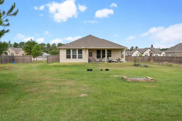 a view of a swimming pool and lounge chairs in back yard of the house