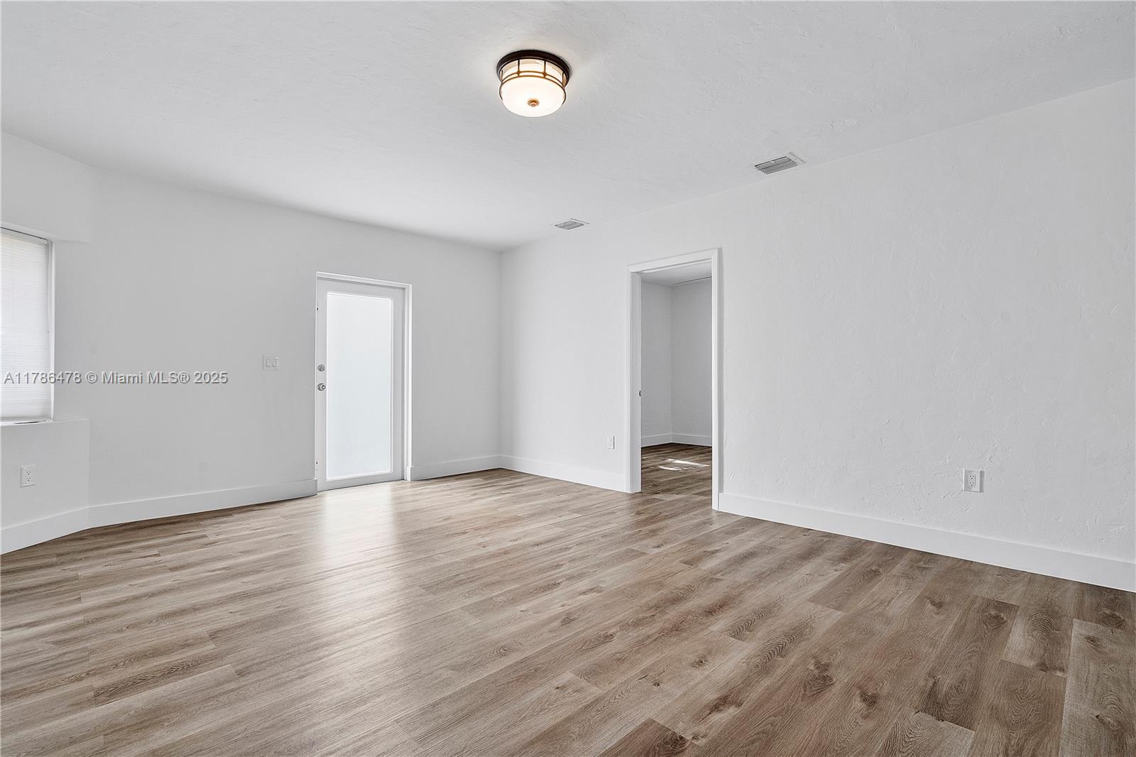8934 Harding Avenue Surfside, FL 33154 - Photo 16 of 52 an empty room with wooden floor and windows