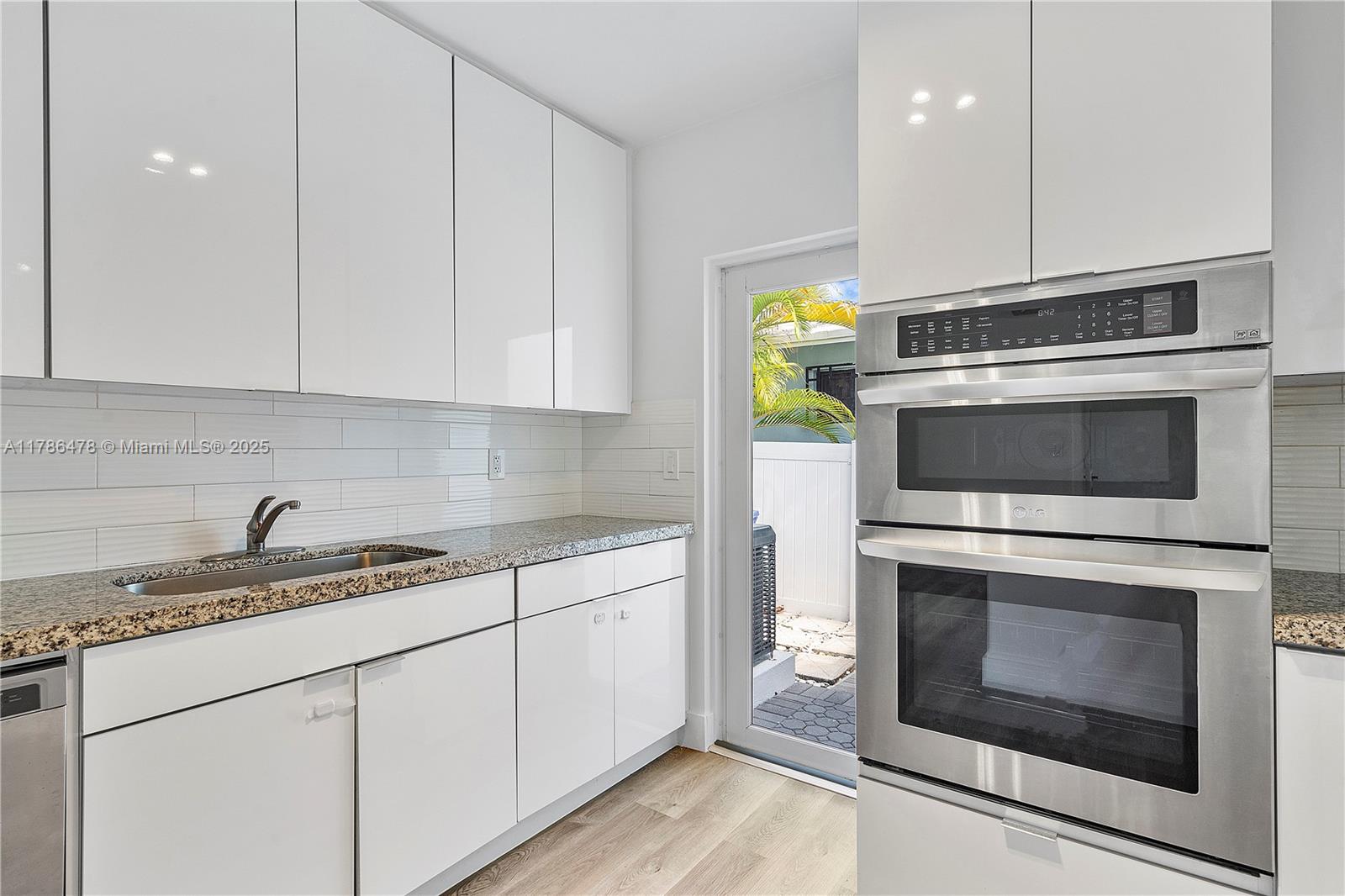 8934 Harding Avenue Surfside, FL 33154 - Photo 21 of 52 a kitchen with granite countertop white cabinets stainless steel appliances and sink