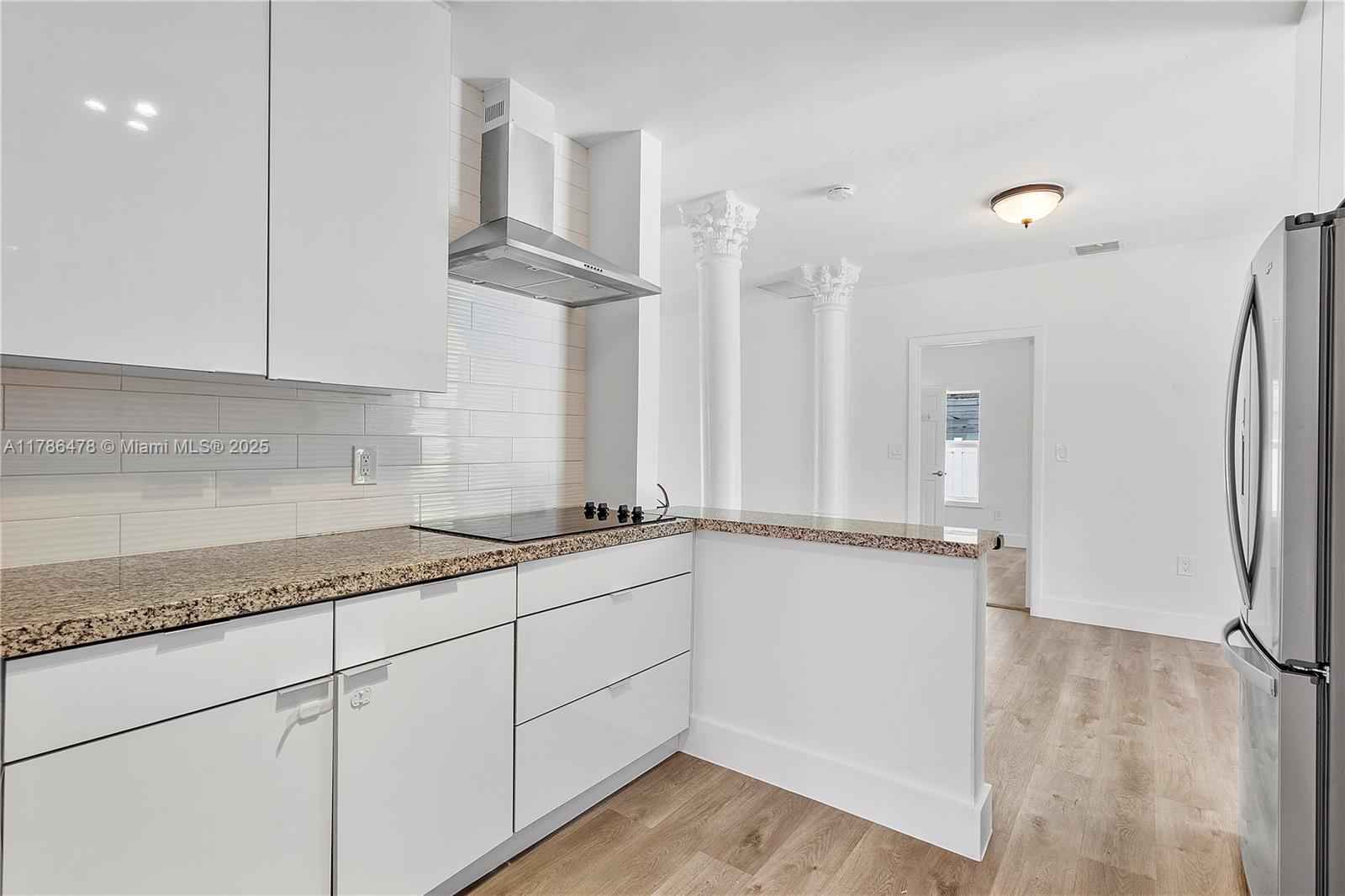8934 Harding Avenue Surfside, FL 33154 - Photo 23 of 52 a kitchen with granite countertop a refrigerator a sink and white cabinets