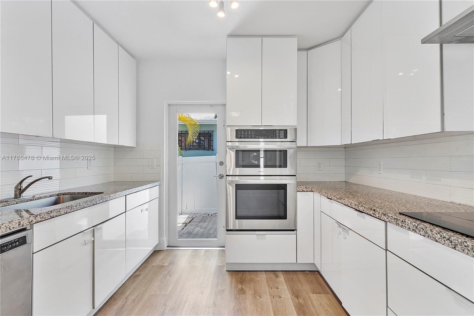 8934 Harding Avenue Surfside, FL 33154 - Photo 26 of 52 a kitchen with stainless steel appliances granite countertop a stove a sink and white cabinets