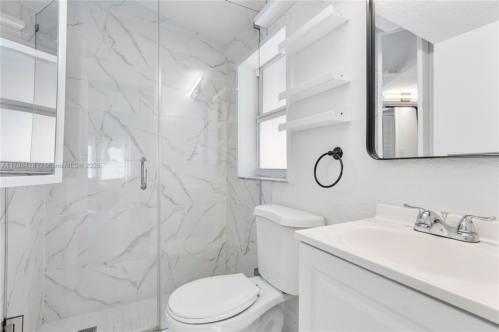 8934 Harding Avenue Surfside, FL 33154 - Photo 30 of 52 a bathroom with a toilet sink and mirror