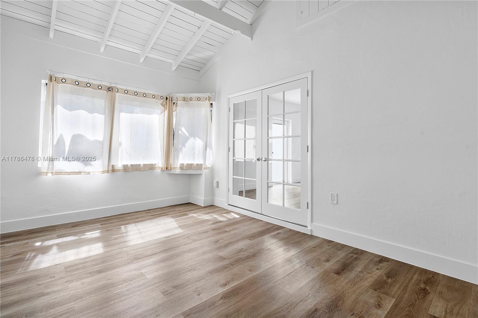 8934 Harding Avenue Surfside, FL 33154 - Photo 31 of 52 an empty room with wooden floor and windows