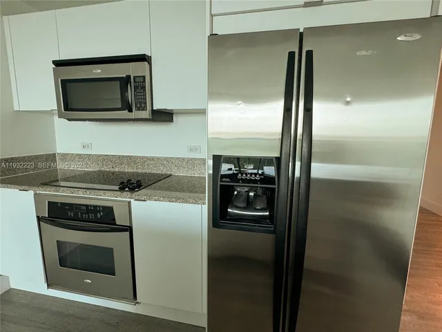 a kitchen with sink a refrigerator and wooden floor