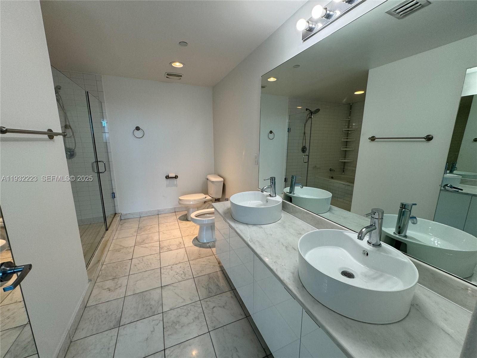 888 Biscayne Boulevard, Unit 709 Miami, FL 33132 - Photo 23 of 48 a bathroom with a double vanity sink a mirror and a shower