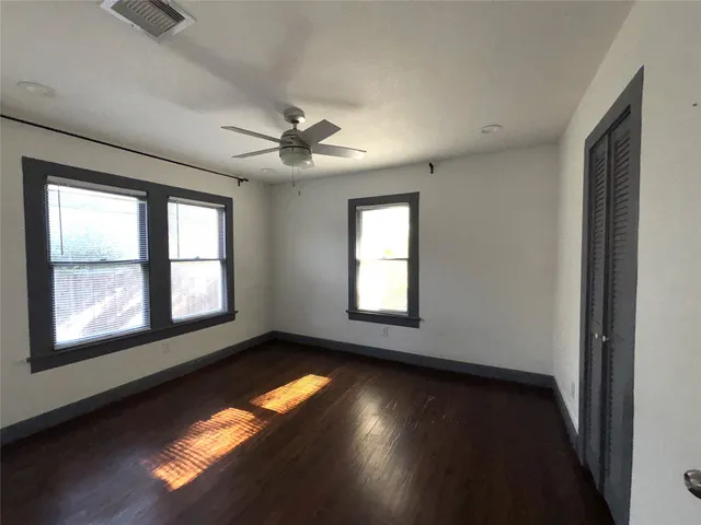 a view of empty room with wooden floor and fan