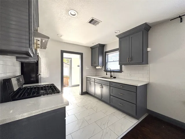 a kitchen with granite countertop a stove sink and cabinets