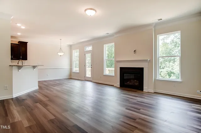 an empty room with wooden floor a fireplace and windows