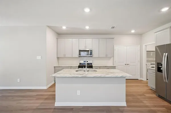 a large kitchen with stainless steel appliances granite countertop a sink a stove a refrigerator and cabinets
