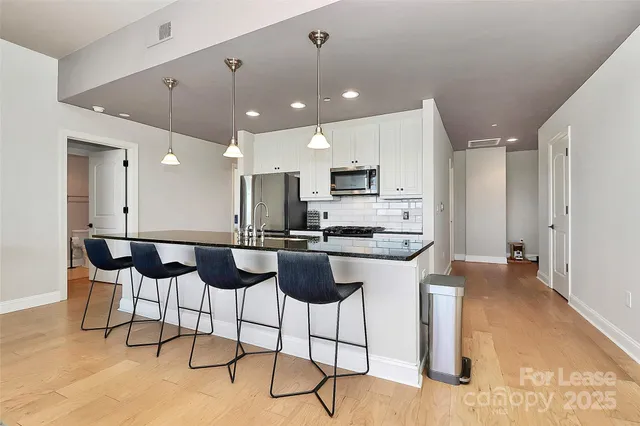 a kitchen with stainless steel appliances kitchen island granite countertop a dining table chairs and sink