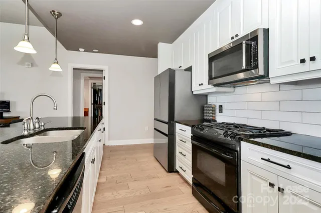 a kitchen with granite countertop a sink stainless steel appliances and cabinets