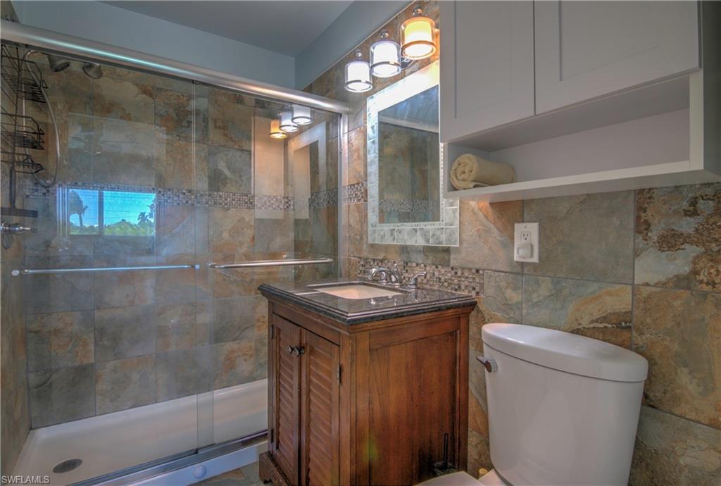 3215 Stringfellow Road, Unit 2A St. James City, FL 33956 - Photo 14 of 31 a bathroom with a granite countertop sink a toilet and shower