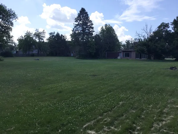 a white house with a big yard and large trees