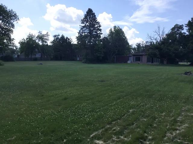 a white house with a big yard and large trees