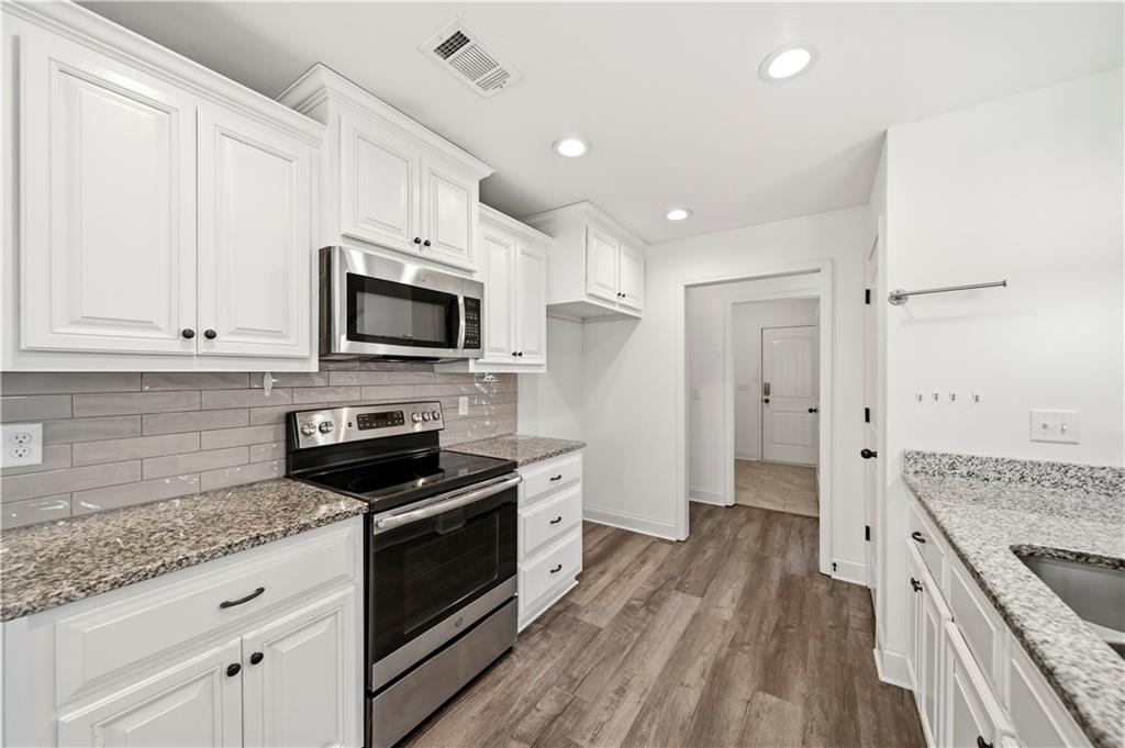 108 Watts Drive Perry, GA 31069 - Photo 15 of 34 a kitchen with granite countertop a stove top oven a sink dishwasher a refrigerator and white cabinets with wooden floor