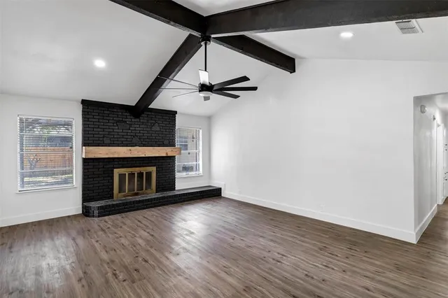 a view of an empty room with wooden floor fireplace and a window